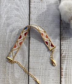 the beaded bracelet is hanging on a wooden surface with a cotton ball in the background