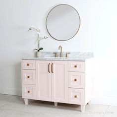 a bathroom vanity with a round mirror above it and marble counter top on the side