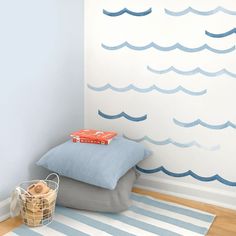 a blue and white wall with waves painted on it, next to a basket full of books