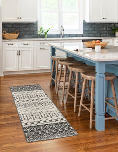 a kitchen with white cabinets and blue island