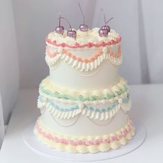 a three tiered cake with white frosting and colorful decorations