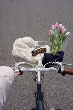 a person riding a bike with flowers in the basket on the handlebars,