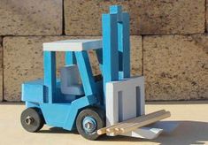 a small blue forklift sitting on top of a cement floor next to a brick wall