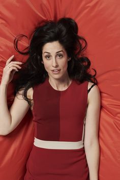 a woman laying on top of a red sheet