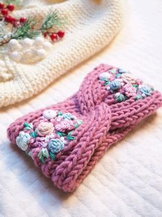 two knitted mittens sitting on top of a bed next to a white blanket