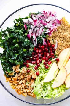 a salad with apples, lettuce, nuts and cranberries in a glass bowl