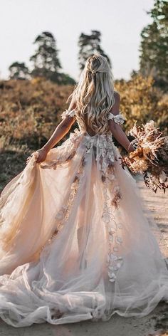 a woman in a dress walking down a dirt road