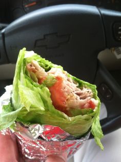 a hand holding a wrap filled with lettuce and meat