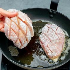 two pieces of meat being cooked in a frying pan