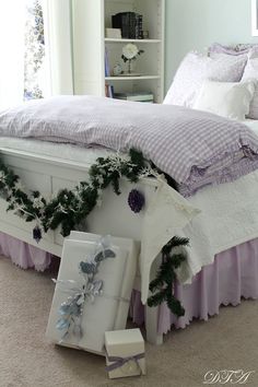 a white bed with purple ruffled bedspread and garland on the headboard