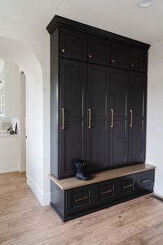 a large black cabinet in the middle of a room with wood floors and white walls