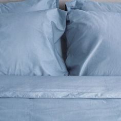 a bed with blue sheets and pillows on it