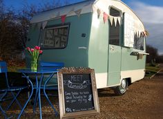 an rv parked in the dirt with a chalkboard sign