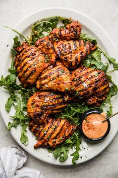 grilled chicken on a plate with lettuce and sauce