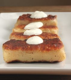 three pieces of bread with white cream on them sitting on top of a white plate