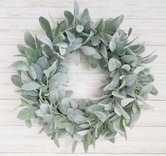 a wreath with green leaves on a white wooden background