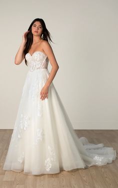 a woman in a white wedding dress posing for the camera with her hand on her head