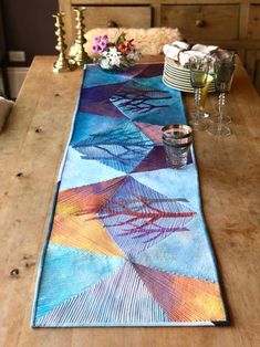 a table runner is on top of a wooden table next to two glasses and silverware