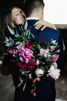 a bride and groom embracing each other in front of a window with flowers on it