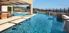 an outdoor swimming pool next to a covered patio with table and chairs on the side