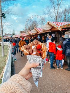 a person is holding up a pastry in front of a crowd at an outdoor fair