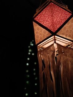 a red and white lamp hanging from the ceiling in front of a building at night