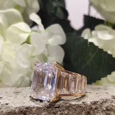 an image of a ring on top of a rock with flowers in the back ground