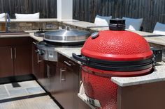 a big red grill sitting on top of a kitchen counter next to a sink and oven