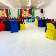 a room filled with tables and chairs covered in blue, yellow and red cloths