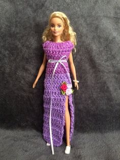 a barbie doll wearing a purple crocheted dress and holding a flower in her hand