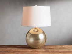 a table lamp with a white shade on it sitting on top of a wooden table