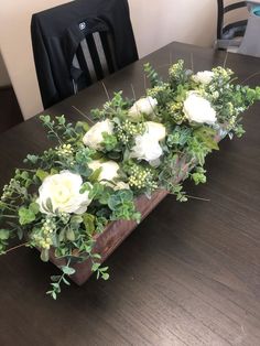 a wooden table topped with white flowers and greenery