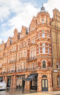 an old building with many windows and balconies on the top floor, next to a white van parked in front of it