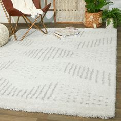 a white rug with lines on it in front of a chair and potted plant