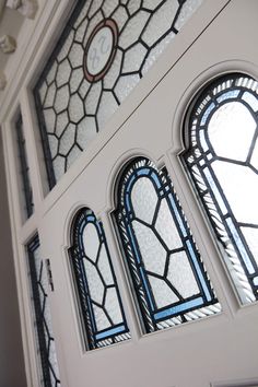 three stained glass windows on the side of a white door with an arched window above them