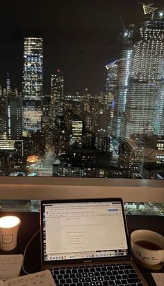 an open laptop computer sitting on top of a desk next to a cup of coffee