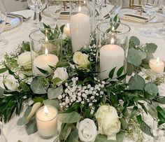 a centerpiece with candles and flowers is displayed on a table at a wedding reception