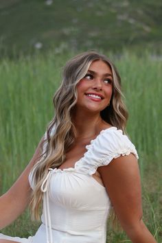 a beautiful woman sitting on top of a grass covered field