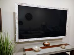 a flat screen tv mounted to the side of a wall next to a wooden table