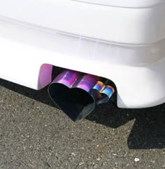 a skateboard laying on the ground next to a white car with purple and blue designs