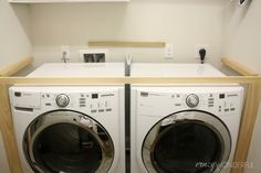 a washer and dryer in a small room with white cabinets on the wall