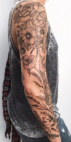 a man with a flower tattoo on his arm and shoulder is standing in front of a white wall