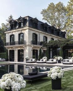 a large white house sitting on top of a lush green field next to a pool