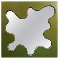 a square shaped mirror sitting on top of a green wall