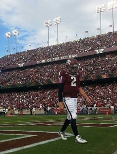 a football player walking on the field in front of an empty stadium filled with people