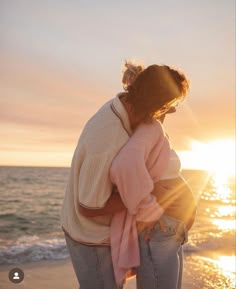 a woman standing on top of a sandy beach next to the ocean at sun set