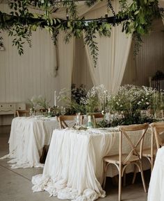 the tables are set with white linens and greenery