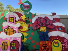 a large christmas sign in front of a building with trees and decorations on the side