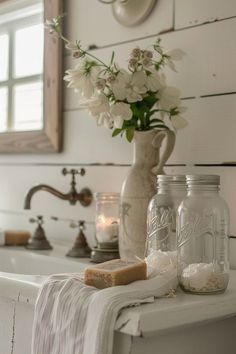 a bathroom sink with flowers and jars on it