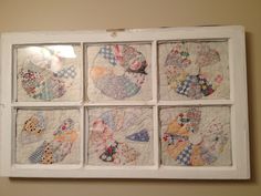 four different quilted pictures hanging on the wall in a window frame with white trim